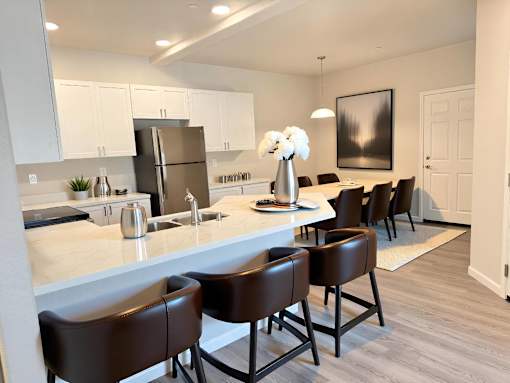 A kitchen with brown chairs and a white counter.