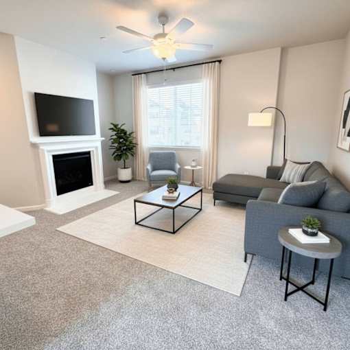 A living room with a grey couch, a white rug, and a fireplace.
