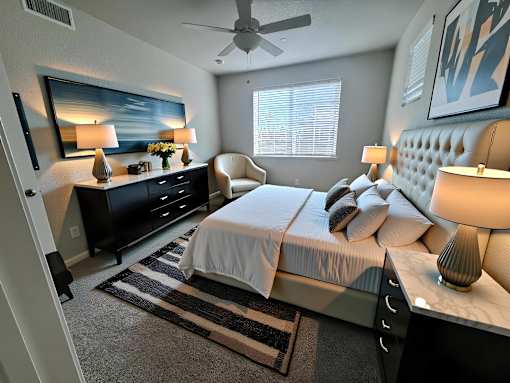 A bedroom with a large bed, a dresser, and a ceiling fan.