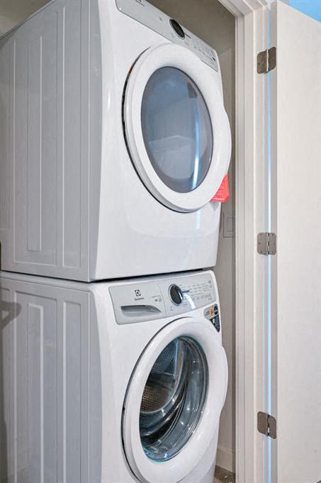 Two white front loading washing machines stacked on top of each other.