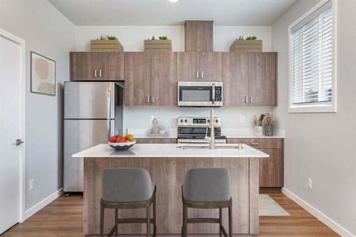 A kitchen with a white counter top and grey chairs.