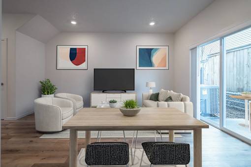 A modern living room with a television, two chairs, a table, and a potted plant.