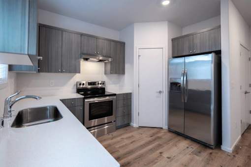 A modern kitchen with a sink, stove, and refrigerator.