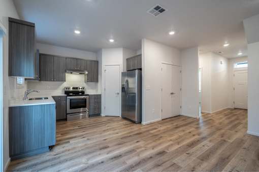 A modern kitchen with wooden floors and stainless steel appliances.