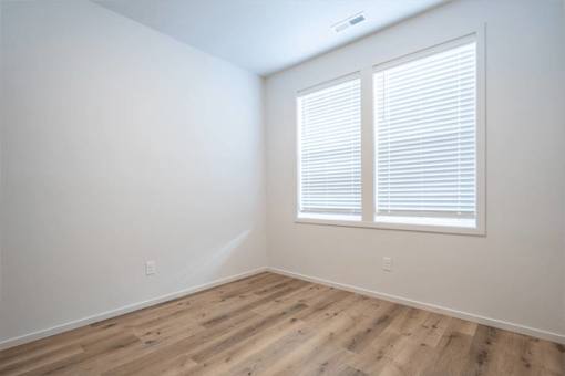 A room with wooden flooring and a window with blinds.