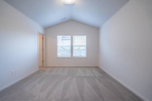 A room with a carpeted floor and a window with blinds.
