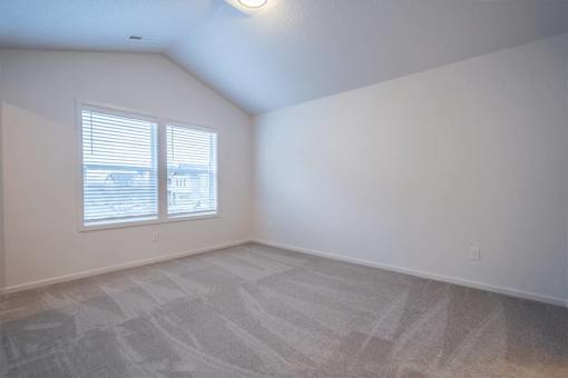 A room with a carpeted floor and a window with blinds.