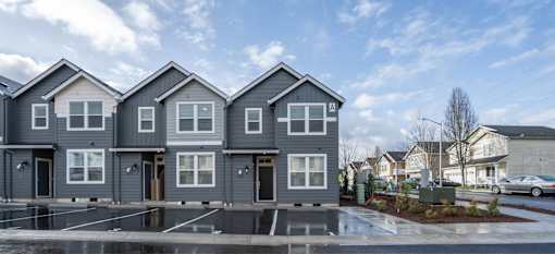 A row of modern houses with grey exteriors and white windows.
