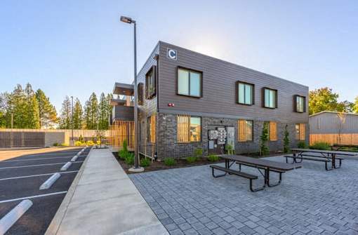 A modern building with a parking lot in front.