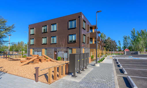 A modern building with a parking lot in front.