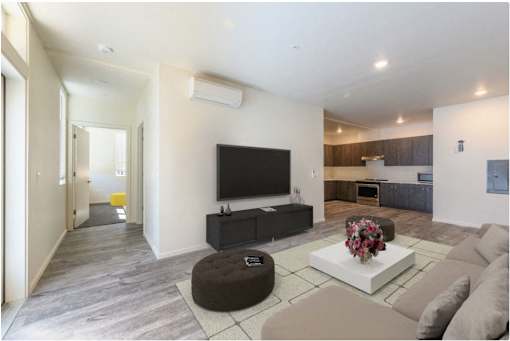 A modern living room with a flat screen TV and a brown ottoman.