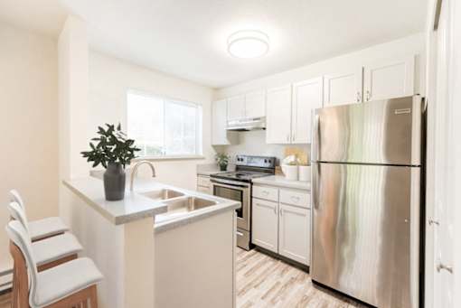 A kitchen with a white refrigerator and white cabinets.