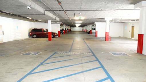 A parking garage with a red car parked in the middle.