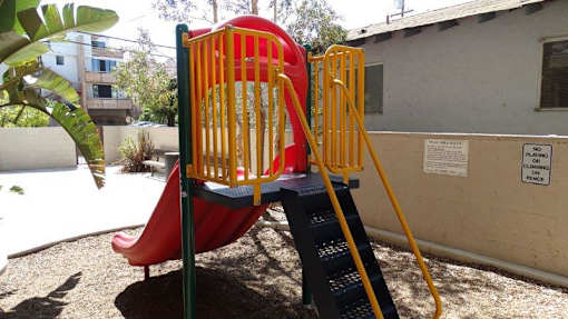 A red slide with a yellow ladder in a playground.