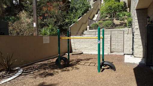 A green and yellow pole stands in a sandy area.