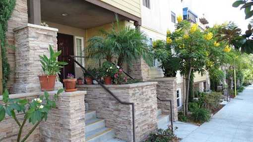A house with a stone wall and a staircase leading to the door.