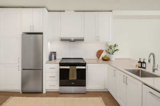 a white kitchen with stainless steel appliances and white cabinets at Liza Apartments, Seattle