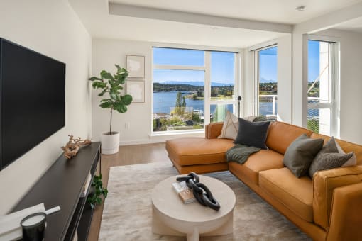 a living room with a leather couch and a television and a view of the water at Liza Apartments, Seattle, Washington, 98102