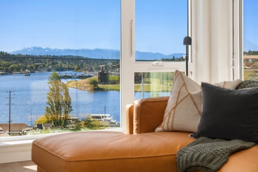 a living room with a couch and a window overlooking a lake and mountains at Liza Apartments, Seattle, Washington