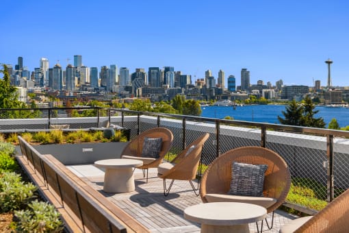 a rooftop deck with chairs and tables with a view of the city at Liza Apartments, Seattle, 98102