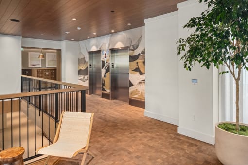 the lobby of a hotel with a chair and a tree at Liza Apartments, Seattle, 98102