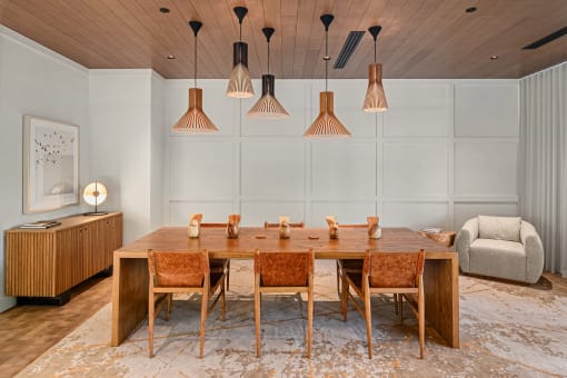 a dining room with a wooden table and chairs and hanging lamps at Liza Apartments, Washington