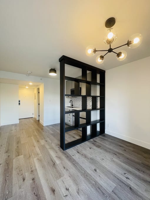 a black shelving unit in the center of a living room with wood flooring