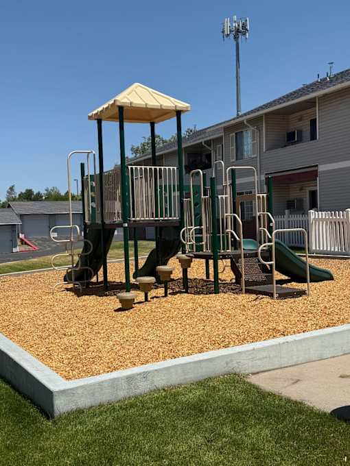 A playground with a yellow canopy and a green slide.