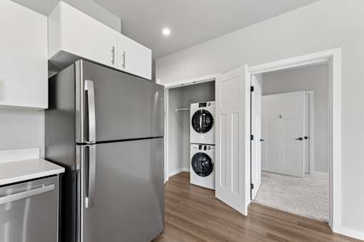 A modern kitchen with a refrigerator, dishwasher, and washing machine.