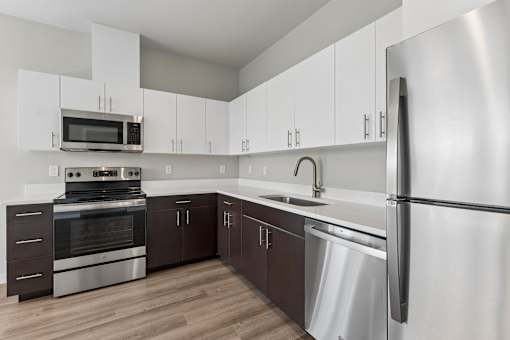 A modern kitchen with stainless steel appliances and wooden floors.