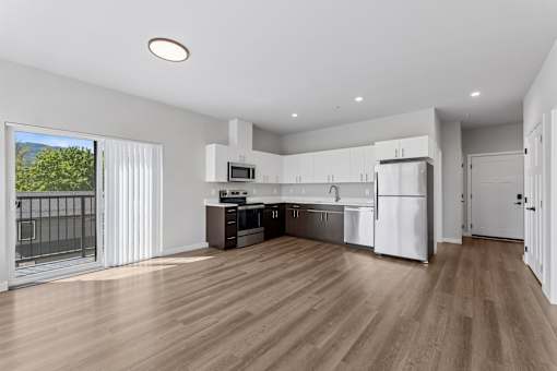 A modern kitchen with wooden floors and white appliances.