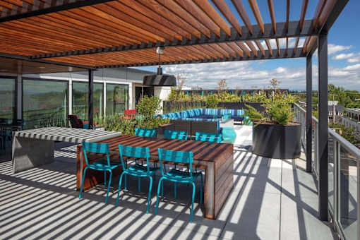 A wooden table with blue chairs is on a patio.