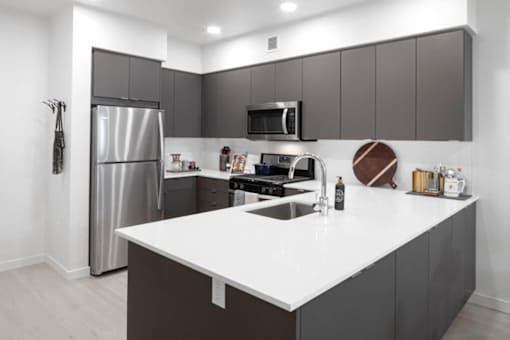 A modern kitchen with a white countertop and stainless steel appliances.