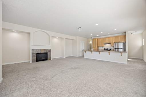 A spacious living room with a fireplace and a kitchen area in the background at Springwater Crossing apartments in Gresham, Oregon 97030