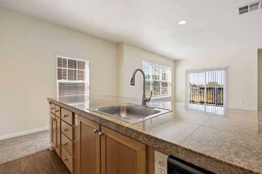 Kitchen island with wooden cabinets overlooking living room with windows at Springwater Crossing apartments in Gresham, Oregon 97030