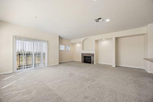 A spacious living room with a fireplace and sliding glass doors leading to patio at Springwater Crossing apartments in Gresham, Oregon 97030