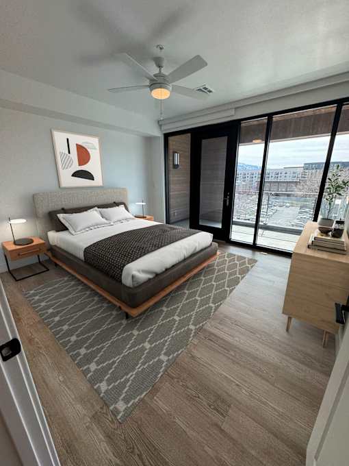 A bedroom with a bed, nightstand, and a ceiling fan.