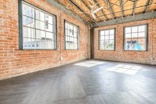 A large empty room with wooden floors and brick walls.