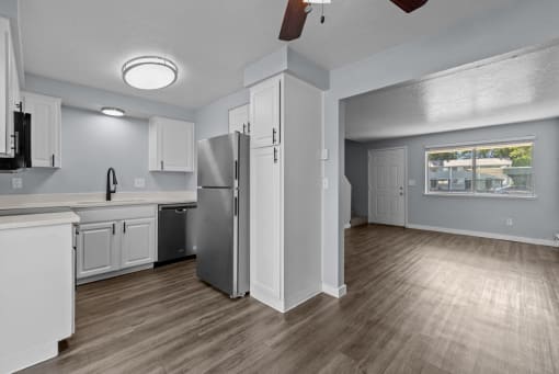an empty kitchen with white cabinets and a stainless steel refrigerator