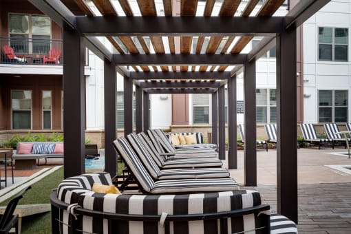 an outdoor lounge area with striped lounge chairs and a pergola