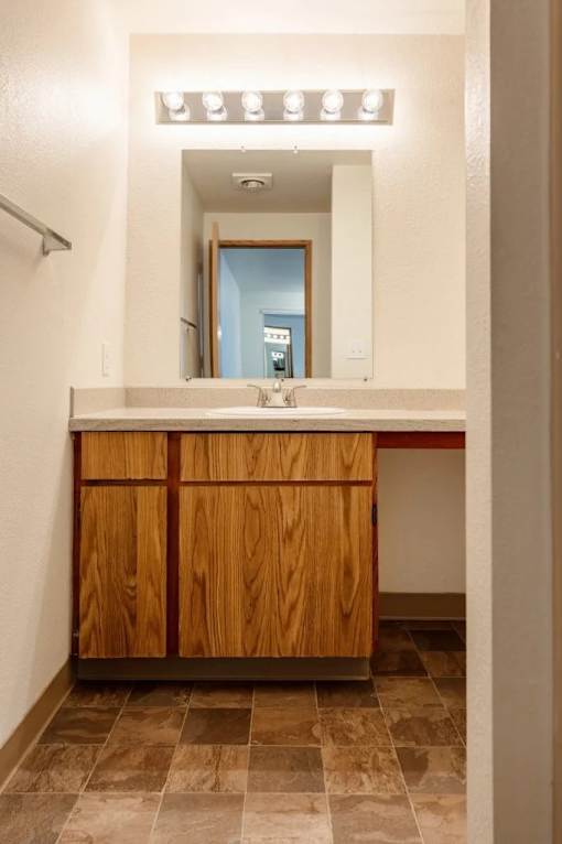 A bathroom with a wooden vanity and a mirror above it.