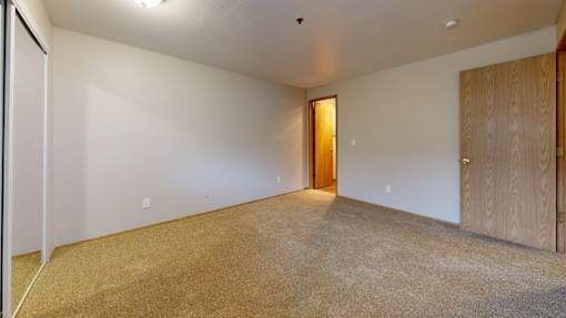 A spacious carpeted bedroom at Heron Hills apartments in Gresham Oregon.