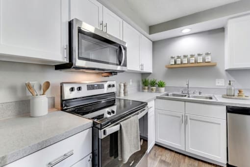 A modern kitchen with white cabinets and a black stove top oven.