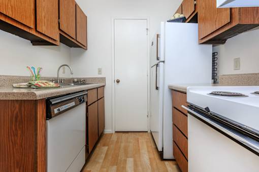 A kitchen with white appliances and wooden cabinets.