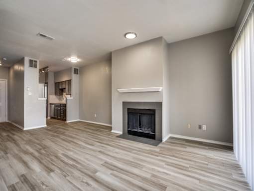 A spacious living room with a fireplace and wood flooring.