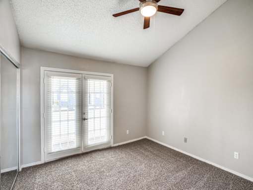 A room with a ceiling fan and a sliding glass door.