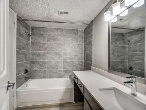 A bathroom with a white tub and sink.