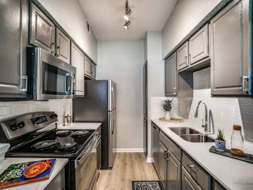 A modern kitchen with stainless steel appliances and wooden flooring.