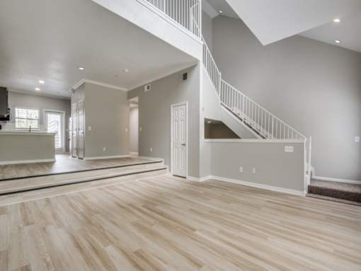 A spacious living room with a staircase leading to the upper floor.