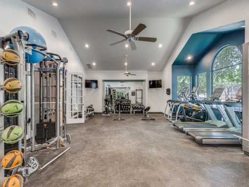 A spacious gym with a variety of equipment including treadmills, weights, and a rowing machine.